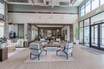 A modern living room with a brick wall and wooden floors.